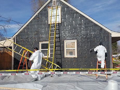 2 men in white jumpsuits siding a house